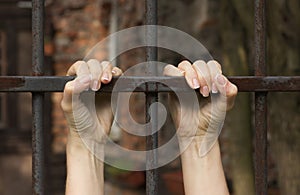 Hands of the prisoner on a steel lattice close-up