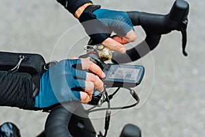 Hands of a professional cyclist on the handlebars with a bicycle computer, close photo