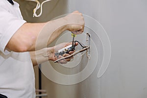 Hands professional during mounting of electrical outlets connector installed in plasterboard drywall for gypsum walls