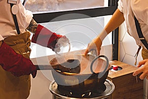 The hands of professional nougat manufacturers in the preparation of sweets in the copper kettle on an open flame. Selective focus