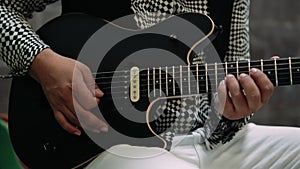 Hands professionally playing a black guitar