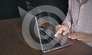 Hands of a programmer types on a laptop displaying programming code, symbolizing coding tech, software development, web