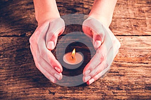 Hands protect candle flame
