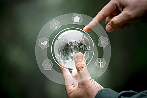 Hands protecting globe of green tree on nature background, ecology and environment. Hand holding green earth ESG icon for