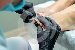 Hands of pudicurist cutting toenails of woman