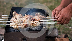 Hands put kebabs on a barbecue