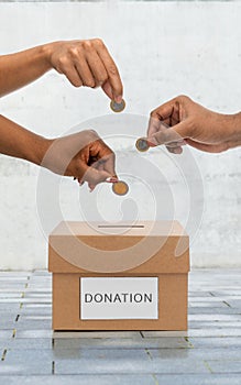 hands putting coins into donation box on street