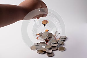 Hands are putting coins in a piggy bank. Money saving concept