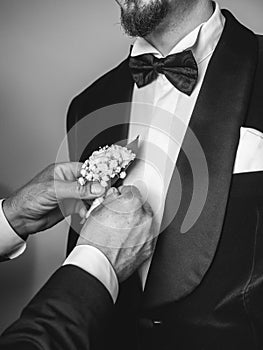 hands putting the groom 's flower at romanian wedding