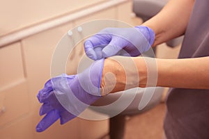 Hands putting on medical purple gloves