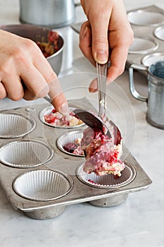 Hands Putting Raspberry Muffin Batter Into Tins photo