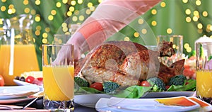 Hands putting roasted turkey on festive table closeup