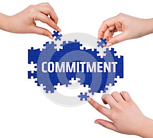 Hands with puzzle making COMMITMENT word