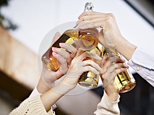 Hands raising beer bottles for a toast