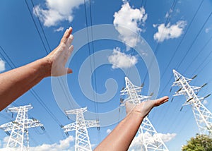 Hands reach for power transmission lines against blue sky