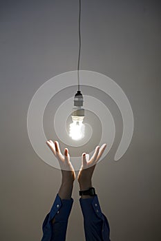 Hands reaching for light bulb