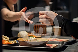 Hands reaching out to each other in the dark over a plate of food. A restaurant