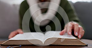 Hands, reading and a book on a table at home for knowledge, research and information. Closeup of a woman with a bible or