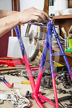 Hands of real bicycle mechanic sanding frame bike