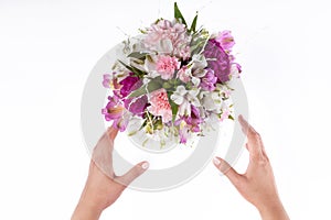 Hands receiving a pastel bouquet from pink and purple gillyflowers and alstroemeria on white