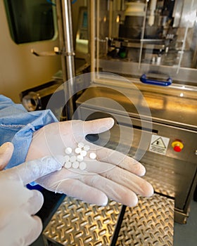 Hands with recently made pills in a drug factory