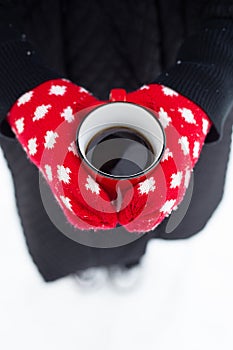 Hands in red gloves hold a mug of hot drink. Beautiful snowy winter  top view