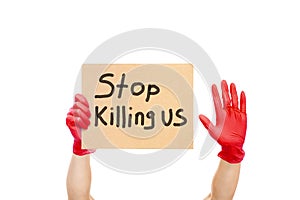 Hands in red gloves are holding a cardboard with the slogan Stop Killing Us.