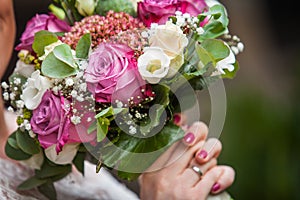 Hands with red nails are holding bouquet made of roses