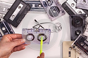 Hands reeling tape back into audio compact cassette