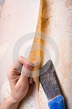 Hands removing old wallpaper
