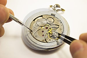 Hands repair an old watch