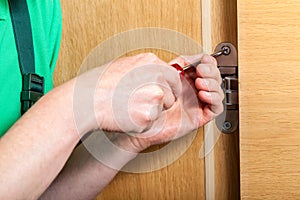 Hands repairing a door hinges