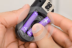 Hands replacing AAA alkaline battery in the electronic device