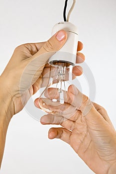 Hands replacing incandescent light bulb