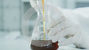 Hands researcher drip oil into test-tube in lab