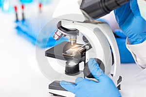 The hands of a researcher are using a microscope to work in the laboratory.