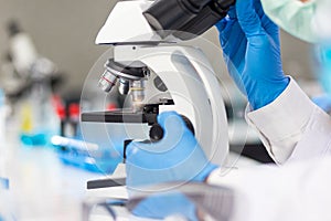 The hands of a researcher are using a microscope to work in the laboratory