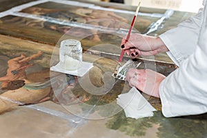 Hands of a Restorer with a Brush: Working on the Restoration of a Painting