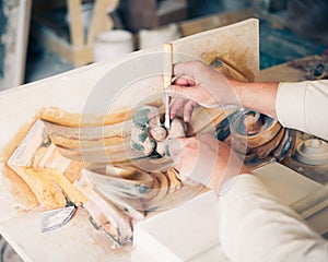 Hands of restorer working with antique decor