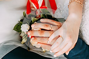 Hands with rings on the fingers of the bride and groom on the background of a wedding bouquet