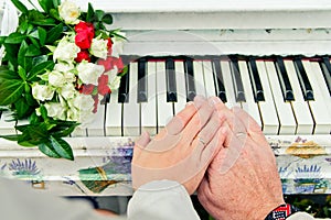 Hands with rings on piano. Beside bouquet of roses