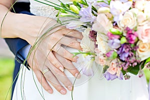 Hands and rings on wedding bouquet