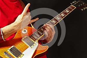 Hands of rock guitarist playing the electric guitar on dark background