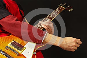 Hands of rock guitarist playing the guitar on dark background