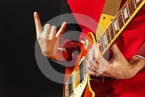 Hands of rock musician playing the guitar on dark background