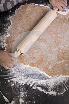 Hands rolling out dough in flour