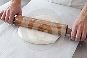 Hands with rolling pin spreading the sugar paste