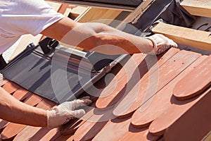 Hands of roofer laying tile on the roof. Installing natural red tile