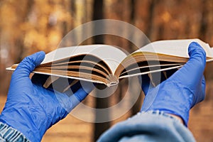 Hands in rubber gloves hold book in forest