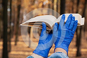 Hands in rubber gloves hold book in forest